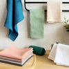 A collection of light green and pink waffle weave towels are displayed on a wooden surface.