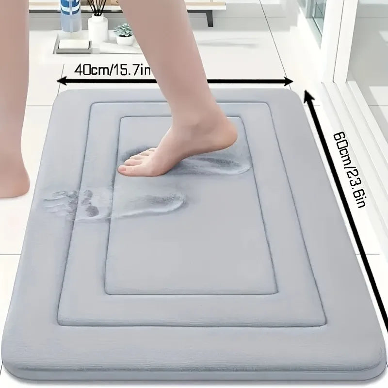 A gray non-slip absorbent bath mat is shown with a foot placed on it, demonstrating its size and function.