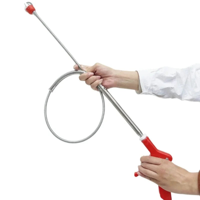 A hand is using a heavy duty sink and drain unclogging tool to clear a clog.