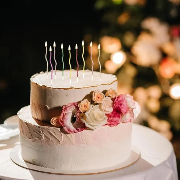 Zweistöckiges Kuchenmodell mit rosa Glasur und sechs farbenfrohen Geburtstagkerzen.