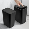 A black 10L small trash can with a press lid is shown on a marble surface, being operated by a hand.