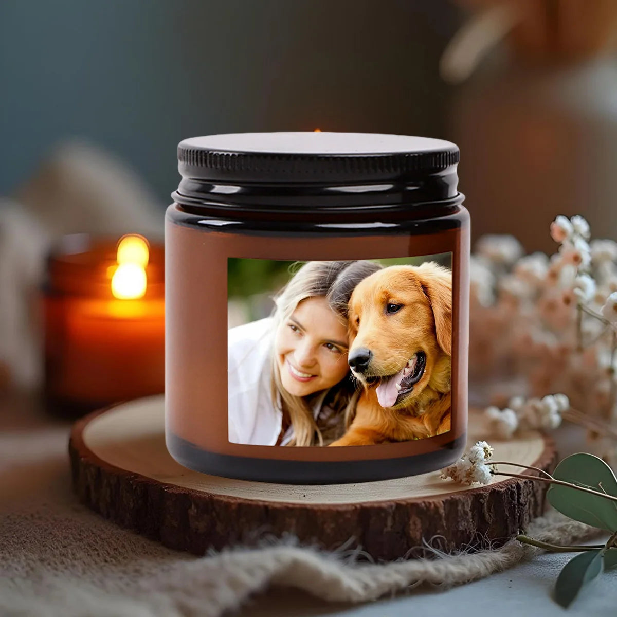 A dark glass jar candle with a custom photo insert showing a woman and a dog, resting on a wooden slice.