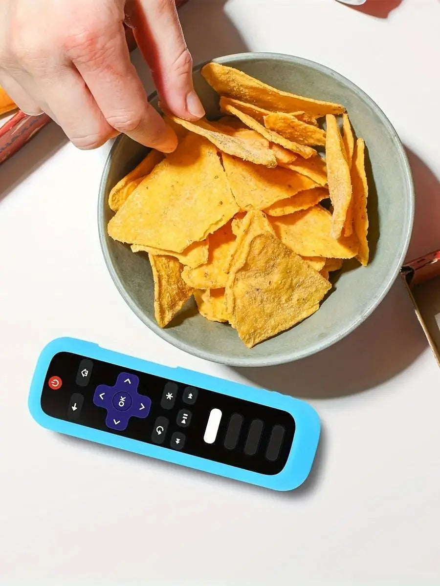 A hand is holding a bowl of yellow tortilla chips next to a blue silicone remote control cover.