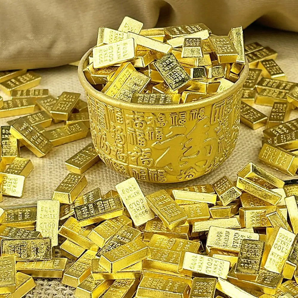 A golden cup filled with small rectangular gold bars and scattered pieces on a beige surface.