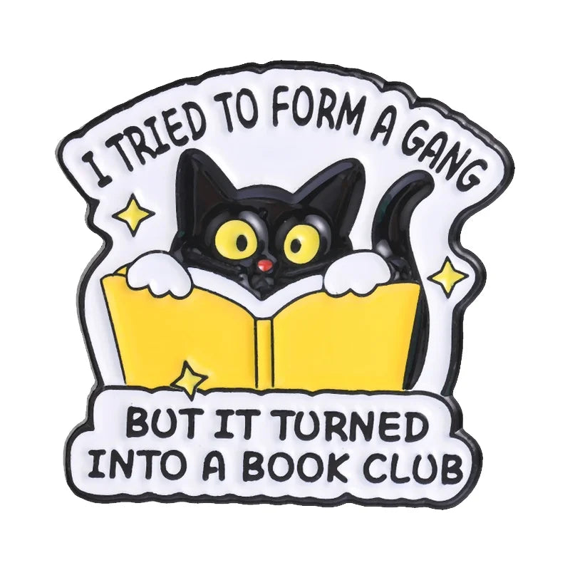 Pin de esmalte con un gato negro mirando por un libro amarillo abierto con el texto 'Intenté formar una pandilla pero no func