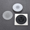 Three round metal drain strainers or hair catchers are displayed on a dark gray surface.