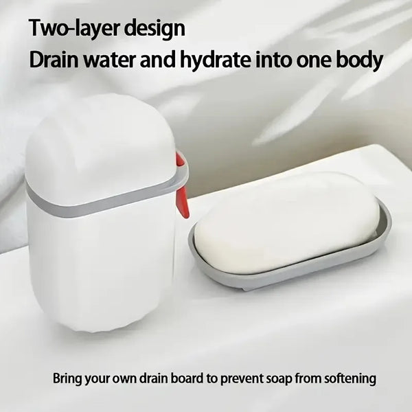 A white two-layer design soap box with a gray lid and a white soap bar resting on a white surface.