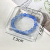 A bracelet of light blue beads is displayed inside a clear plastic jewelry organizer box.