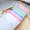 A collection of colorful exfoliating mesh soap pouches with hanging loops displayed on a wooden tray.