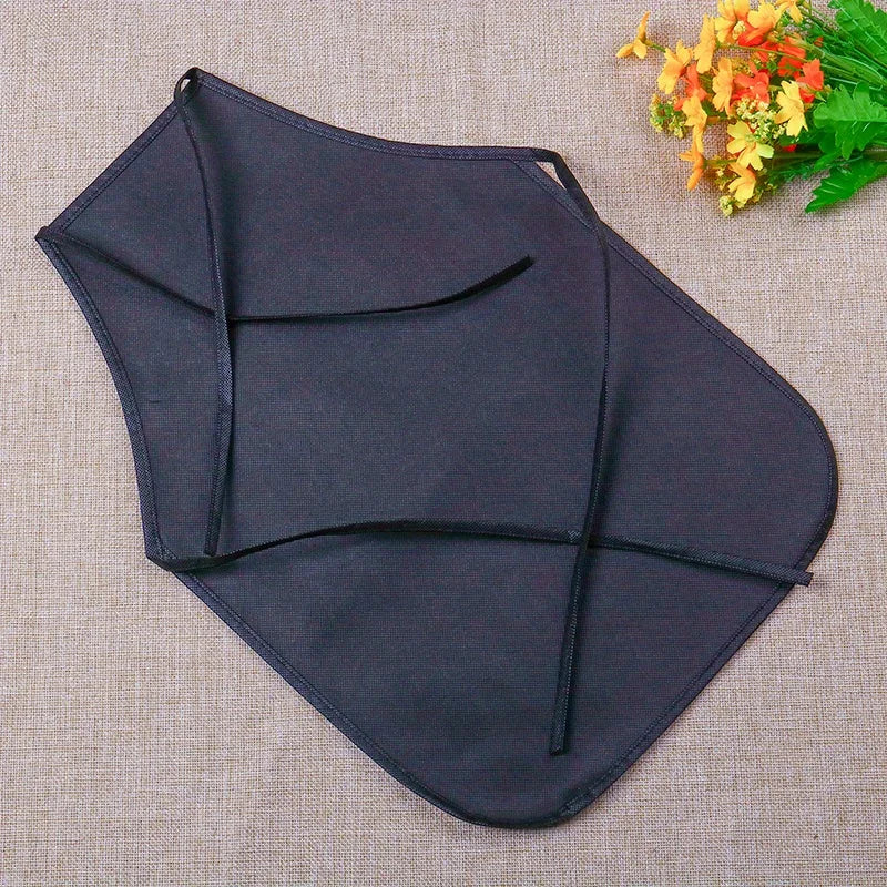 A dark navy blue non-woven craft apron is shown against a beige background with some yellow flowers.