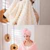 A woman is wrapped in a thick pink microfiber bath towel and matching head wrap.