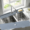 A silver kitchen sink with a silicone splash guard mat is shown under a window.