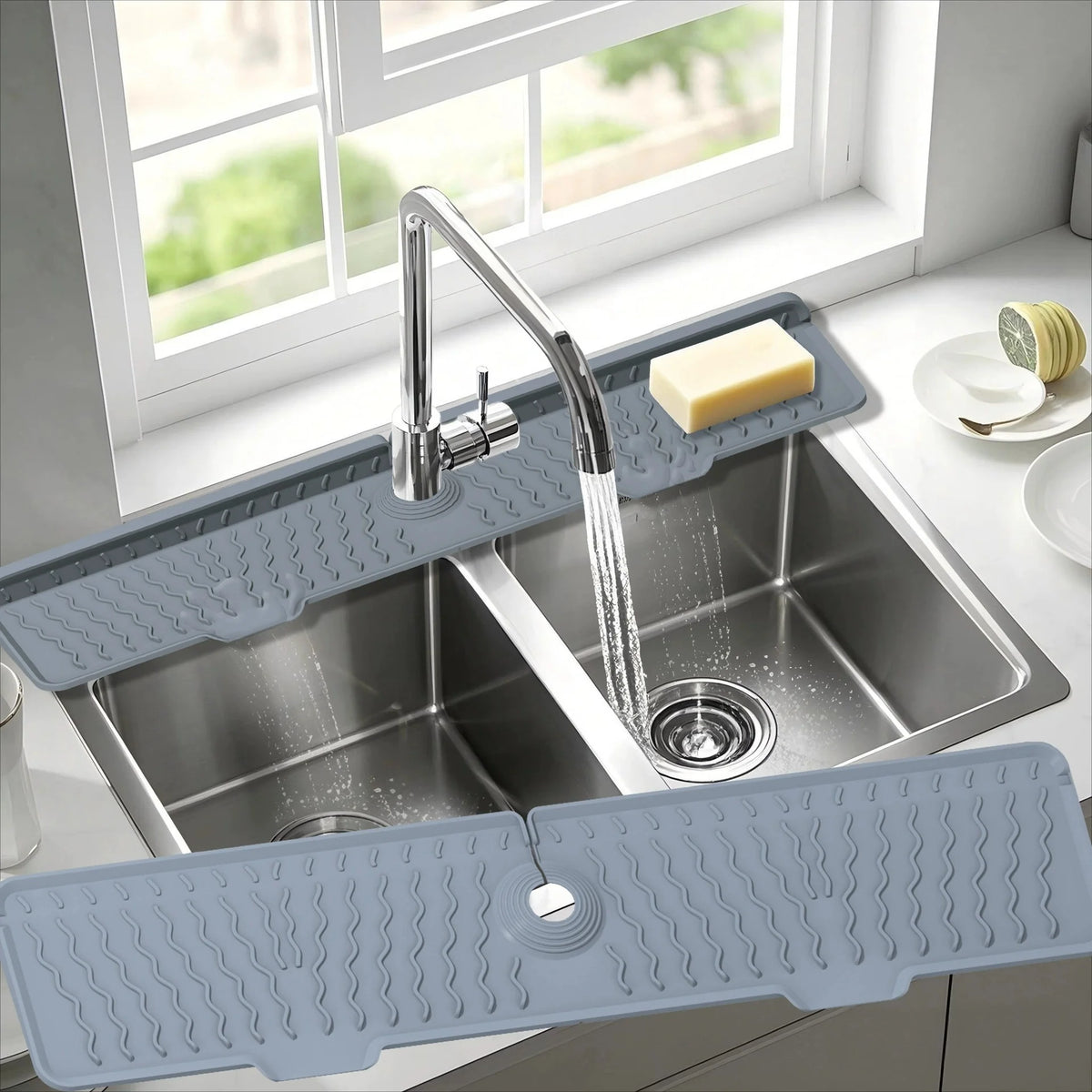 A silver kitchen sink with a silicone splash guard mat is shown under a window.