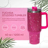 Un vaso tipo tumbler rosa con pedrería y una pajita, mostrado contra un fondo claro.