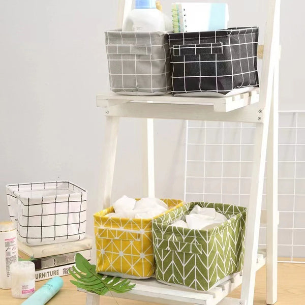A white wooden shelf displaying various storage baskets made of cotton and hemp fabric in black, gray, and lime green pattern