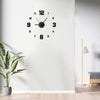A black analog wall clock with Roman numerals is mounted on a white wall above a wooden floor.