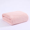 A soft pink thickened microfiber bath towel folded and displayed on a white background.