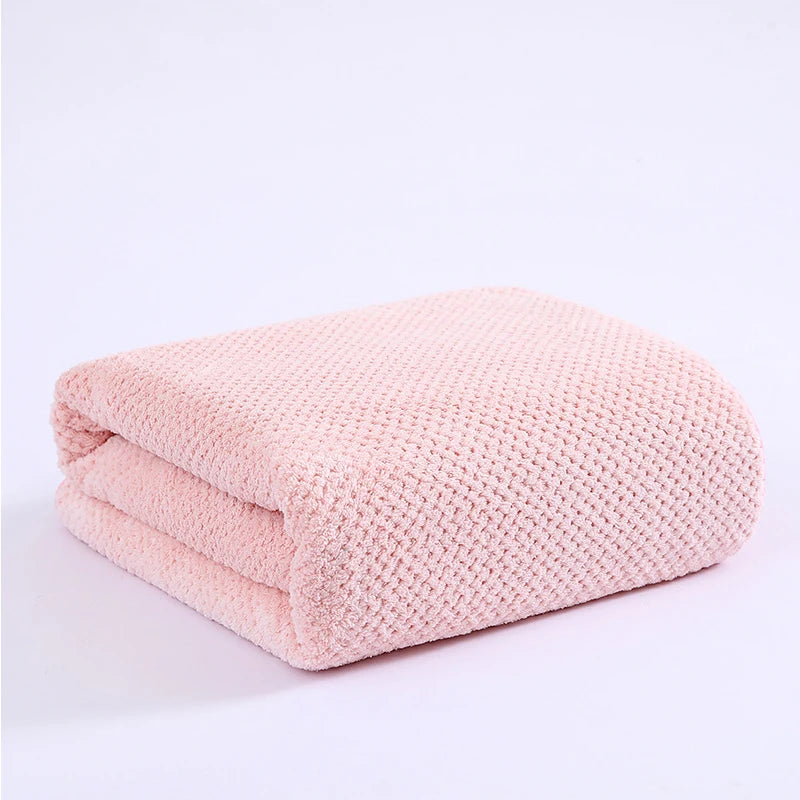 A soft pink thickened microfiber bath towel folded and displayed on a white background.