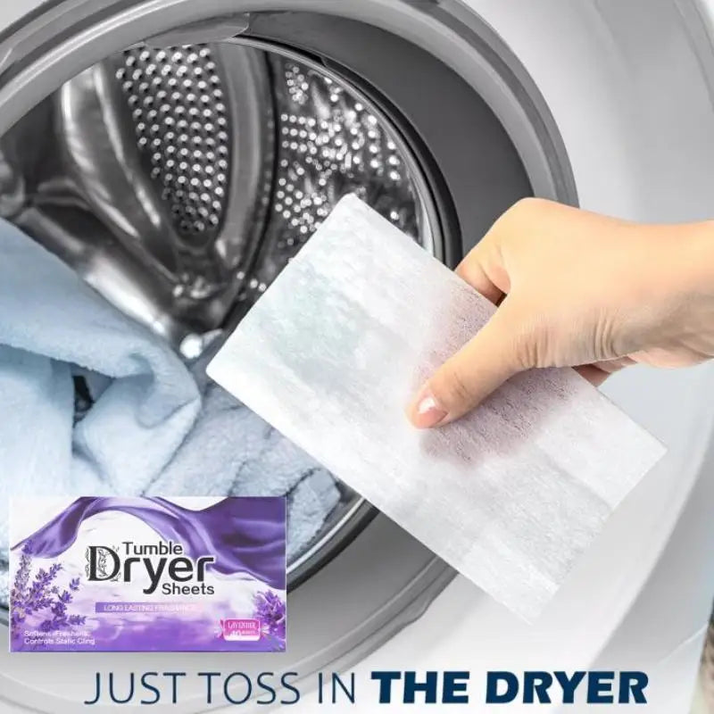 A hand is placing a white dryer sheet into the drum of a washing machine for fabric refreshment.