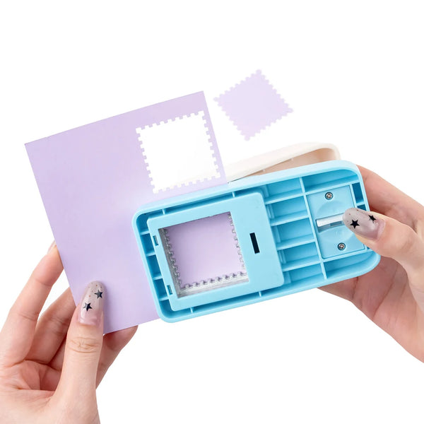 Eine Hand hält einen hellblauen Lever-Stempel für Briefmarken mit einem lila Umschlag und Briefmarkenteilen.
