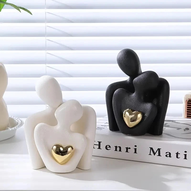 Eine schwarz-weiße skulptierte Figur, die sich umarmt, darstellt romantische Liebe, auf einer weißen Oberfläche.