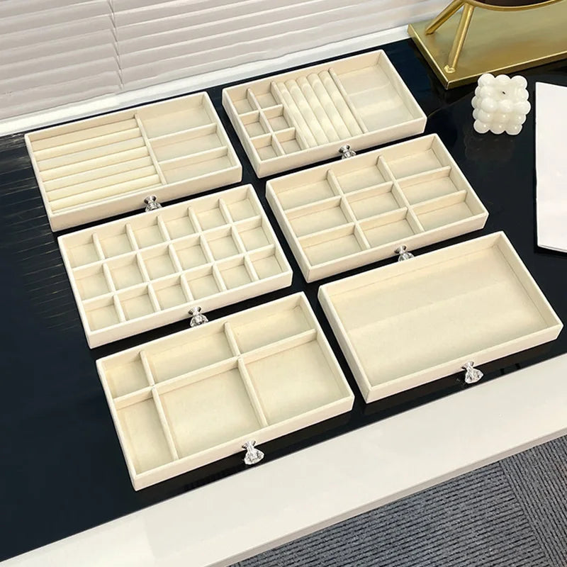 A set of five rectangular light beige desktop jewelry organizer racks with compartments and silver clasps.