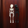 A pair of white and black poseable skull fridge magnets displayed against a dark wood background.