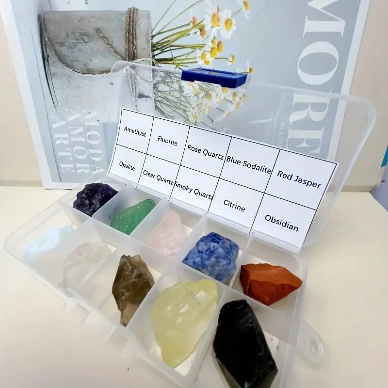 A clear plastic box contains a set of natural crystal stones including amethyst, fluorite, rose quartz, blue sodalite, red ja