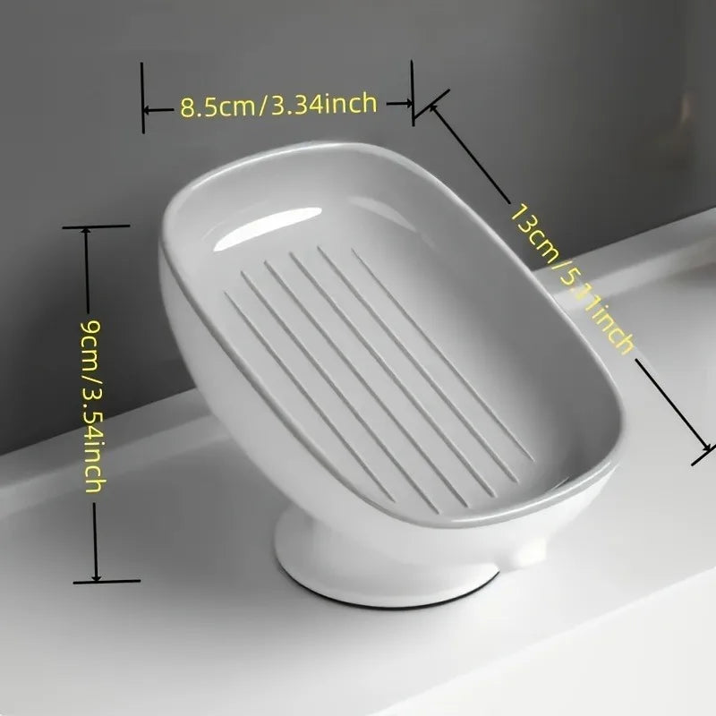 White ceramic countertop soap dish with a slatted drainage area and suction cup base.
