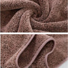 A close-up of a brown, fluffy bath wrap towel being tightly rolled.