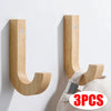 Three natural oak wood wall hooks with screws mounted on a white wall.