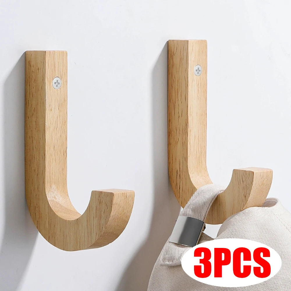 Three natural oak wood wall hooks with screws mounted on a white wall.