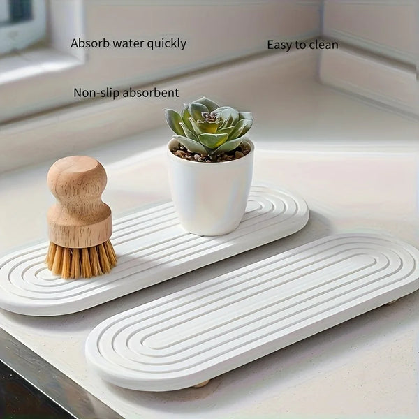 A white natural absorbent stone tray with a wooden brush and a succulent plant on a kitchen counter.