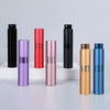 A collection of portable refillable perfume spray bottles in black, pink, and gold tones arranged on a white surface.
