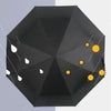 A black folding umbrella shaped like a katana sword with decorative white and yellow sun motifs.