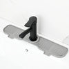 A black flexible silicone sink splash guard drip catcher mat mounted on a white countertop.