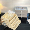 A clear acrylic jewelry organizer rack displaying various gold and silver necklaces, earrings, and rings on a dark surface.