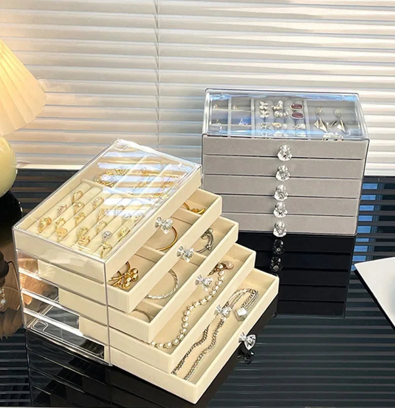 A clear acrylic jewelry organizer rack displaying various gold and silver necklaces, earrings, and rings on a dark surface.