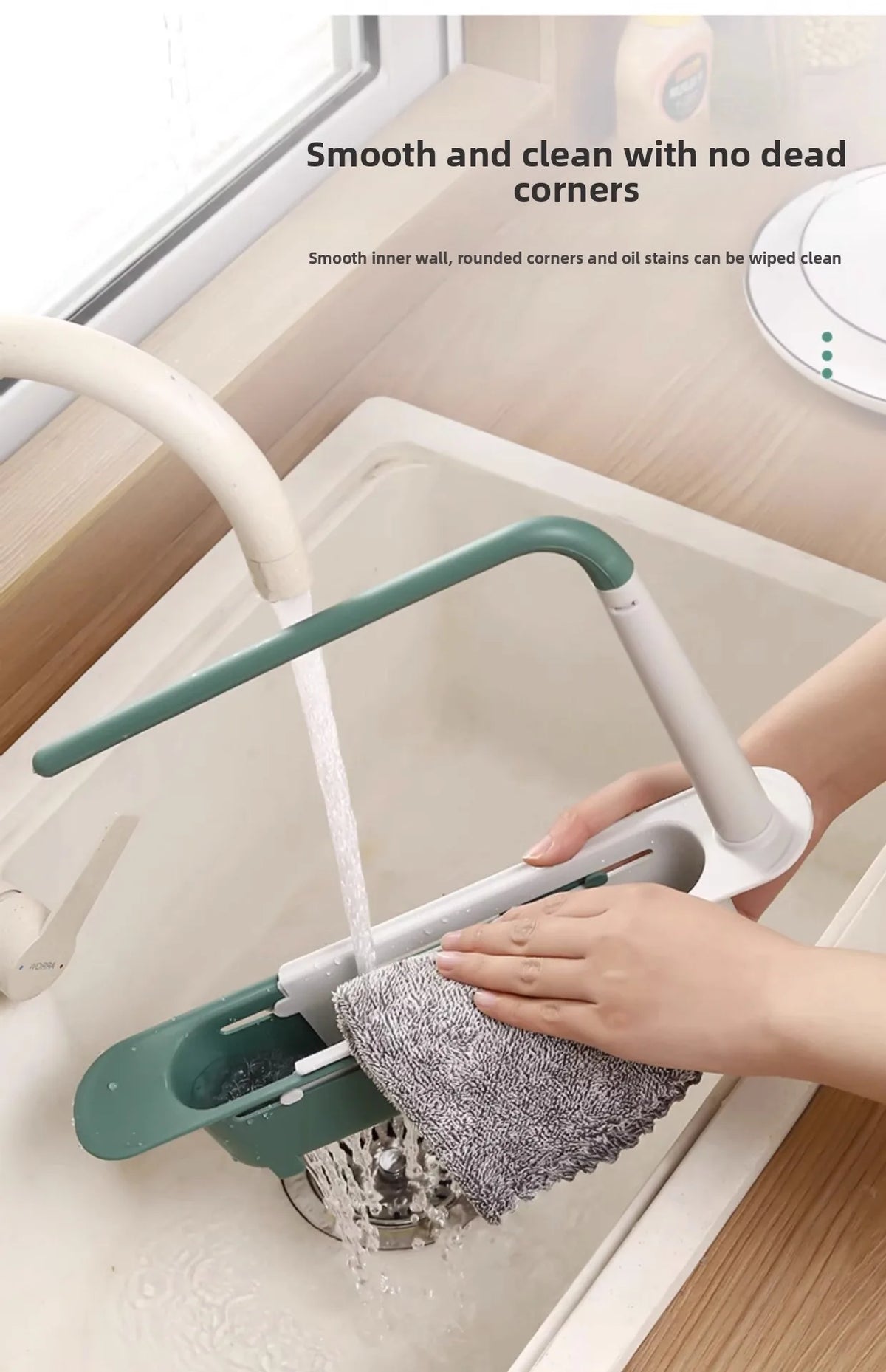 A hand is using an adjustable over-sink dish rack organizer to clean a sink, demonstrating smooth inner corners.