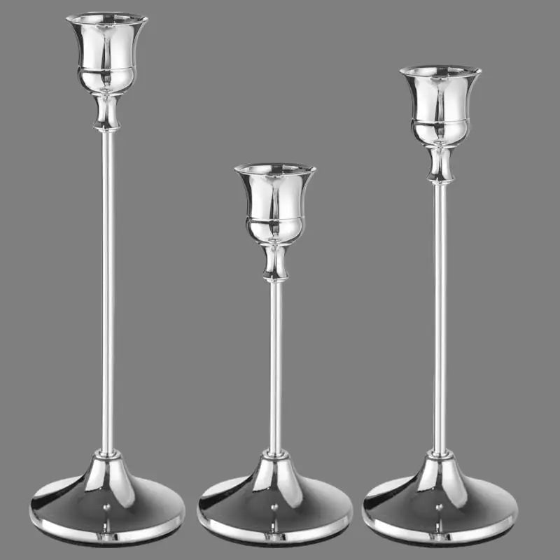 A set of three elegant silver metal candle holders with tall slender stems and flared bases.
