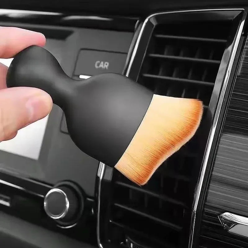 A black multi-surface cleaning brush with a light wood-colored bristles is shown being held in a dark appliance slot.