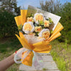 A handmade sunflower crochet bouquet wrapped in yellow paper and tied with a sheer ribbon.