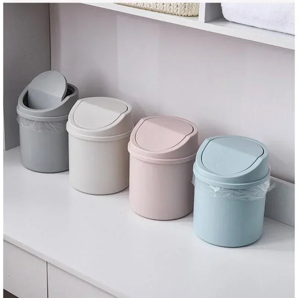 A row of four compact desktop trash cans in various pastel colors, including gray, white, pink, and light blue.