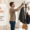 A man and a boy are using a freestanding metal coat rack with hooks to hang coats in a bright hallway.