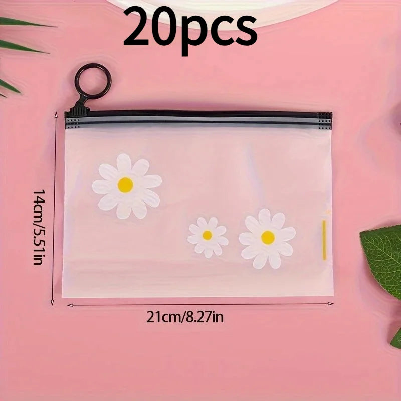 A clear plastic zipper storage bag with a white daisy pattern is shown on a pink background.