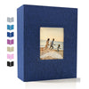 A dark blue linen photo album with a square window displaying a scene of people walking on a beach.