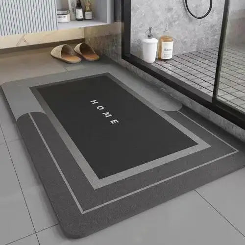 A rectangular gray anti-slip floor mat with the word HOME printed on it, placed on a light tiled floor.