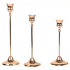 A set of three elegant rose gold metal candle holders with slender stems and flared bases.