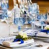 A collection of clear and blue glass champagne flutes are displayed on a table setting.