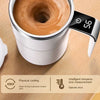 A close-up of an electric self-stirring coffee mug with a stainless steel lid and a digital temperature display showing 56 de